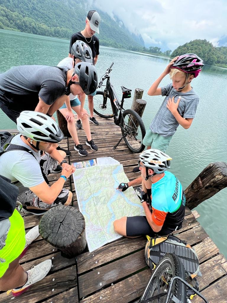 Cyclists Analyzing a Map by the Water Cyclists Analyzing a Map by the Water
